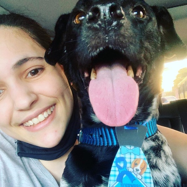 Carolina sorride accanto a un cane nero con collare blu